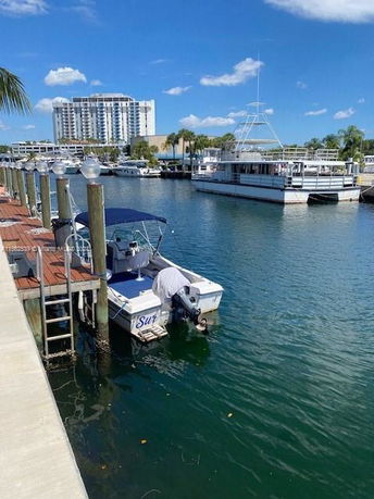 View of boats docked at a marina with a multi-story building in the background.
