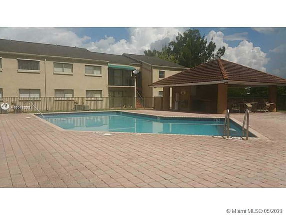 Outdoor swimming pool area adjacent to a two-story building.