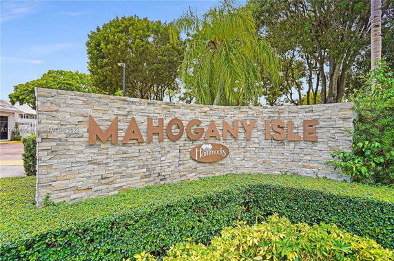 Stone sign for 'Mahogany Isle' with surrounding greenery and trees.