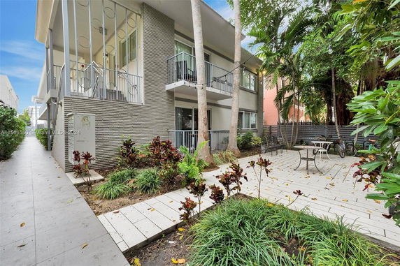 Front view of a two-story building with a small garden and outdoor seating area.