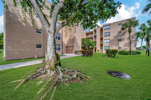 Front view of a multi-story building with balconies and a lawn.