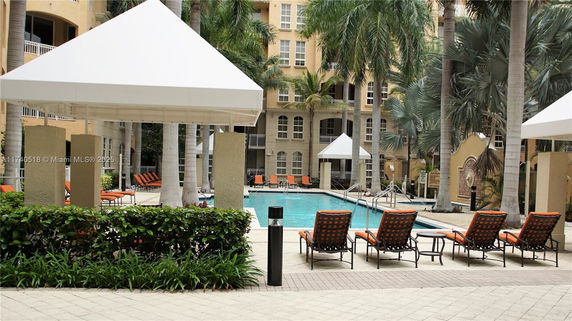 Outdoor swimming pool area with lounge chairs and shaded cabanas.