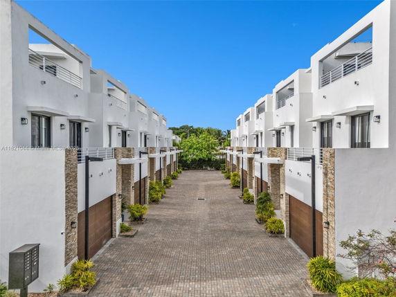 Front view of two rows of modern multi-story townhouses with white facades.
