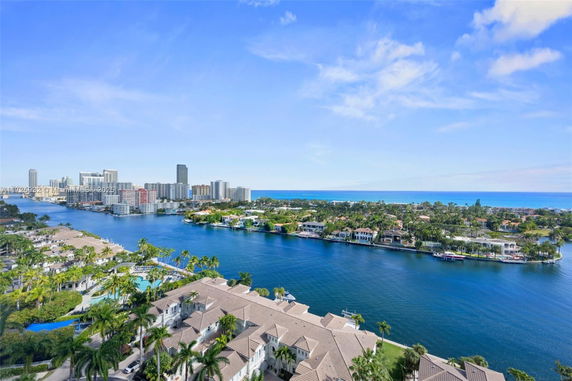 Panoramic view of a river with residential and commercial buildings in the background.