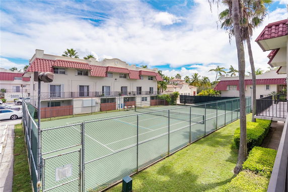 Residential complex with a fenced outdoor tennis court.