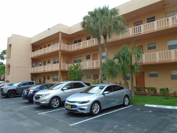 Front view of a three-story residential building with outdoor parking.