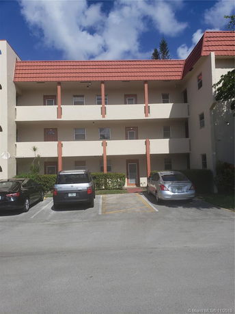 Front view of a three-story apartment building with red roof tiles and balconies.