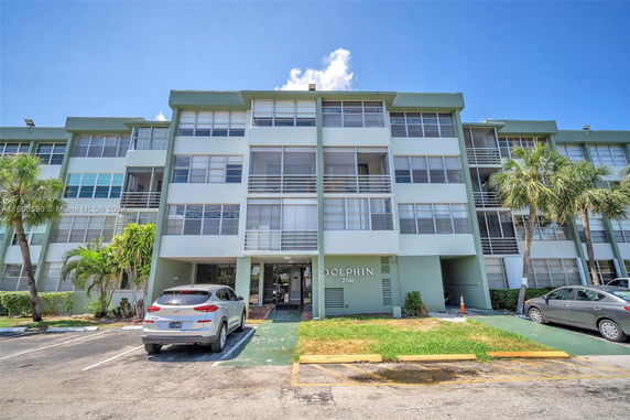 Front view of a multi-story residential building with parking spaces in front.