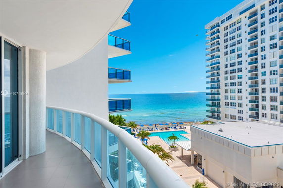 Panoramic view from a balcony overlooking the ocean and surrounding buildings.