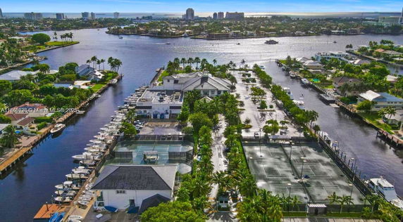 Panoramic view of a waterfront area with buildings, boats, and tennis courts.
