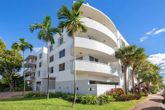 Front view of a multi-story building with balconies and curved architectural design.