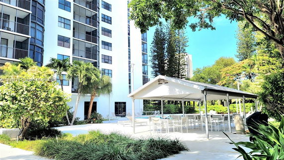 View of a multi-story building with outdoor seating area and surrounding greenery.