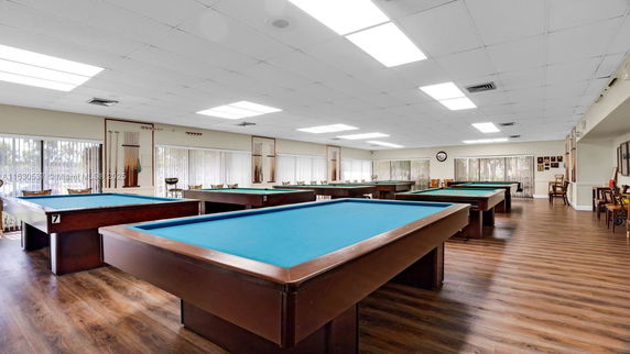 Room with multiple billiard tables and seating area.