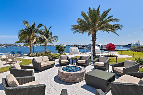 Outdoor seating area with palm trees and a waterfront view.