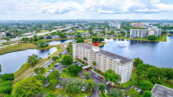 Aerial view of a mid-rise apartment building surrounded by water and greenery.