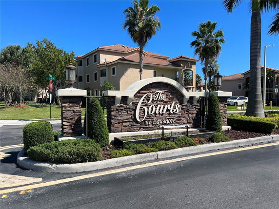 Front view of a residential complex entrance with signage reading 'The Courts at Bayshore'.