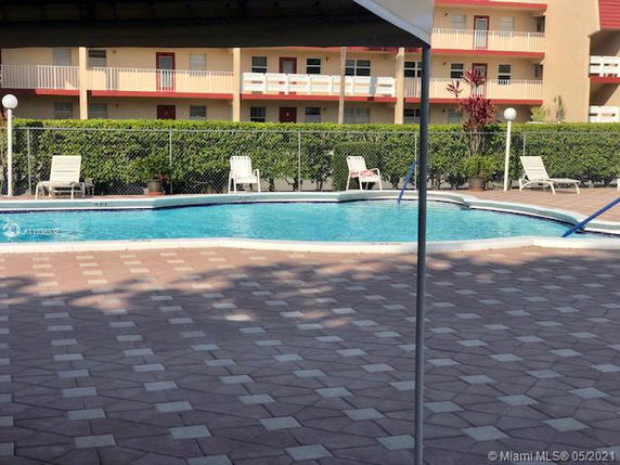 Outdoor swimming pool area with lounge chairs and a fenced boundary.