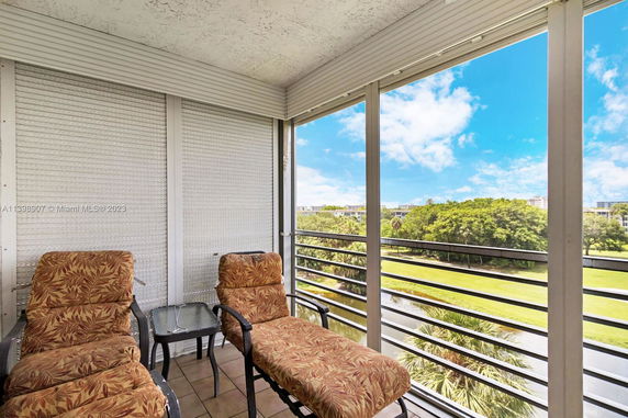 Panoramic view from a balcony showing outdoor surroundings with a blue sky and greenery.