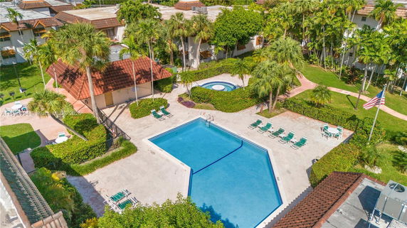 Aerial view of a swimming pool area with surrounding lounge chairs and a hot tub in a residential complex.
