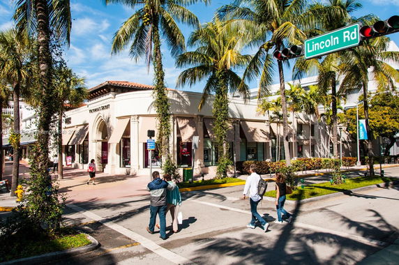 Front view of a two-story commercial building with palm trees lining the street.