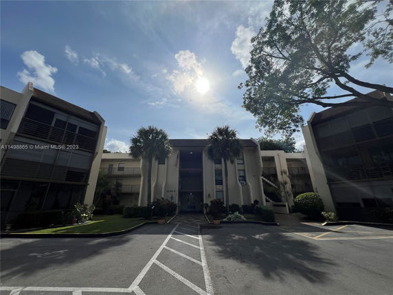 Front view of a multi-story building with adjacent greenery.