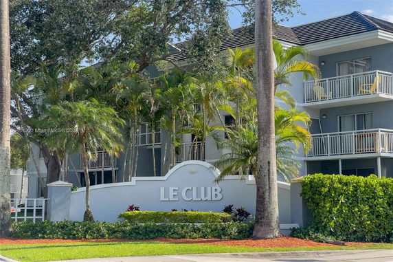 Front view of a multi-story building with balconies and the sign 'LE CLUB' at the entrance.