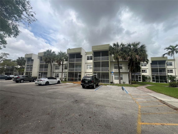 Front view of a multi-story residential building with parking spaces in front.
