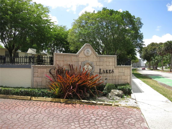 Entrance sign of a residential area with decorative plants.