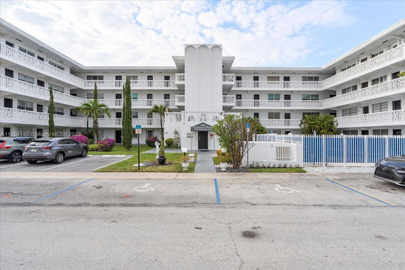 Front view of a multi-story residential building with balconies and parking area.
