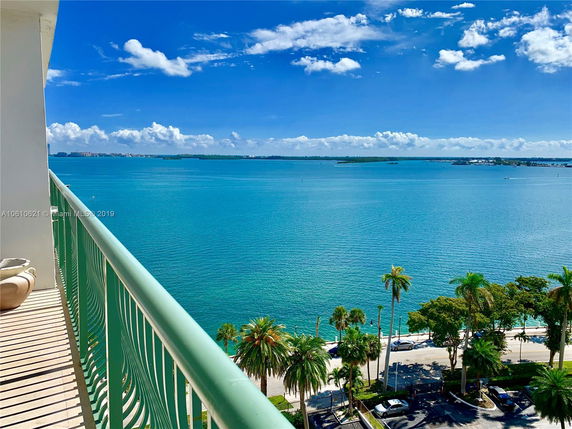 Panoramic view from a high-rise building balcony overlooking a large body of water and distant islands.