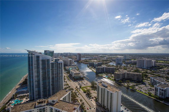 Wide angle view of a coastal cityscape with high-rise buildings and a waterway.