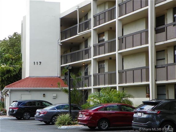 Front view of a multi-story building with balconies and a red-tiled roof section.