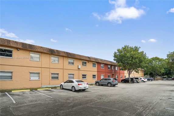Outdoor parking area in front of a two-story building.