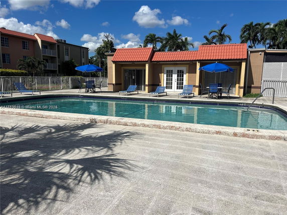 Outdoor swimming pool with lounge chairs and umbrellas.