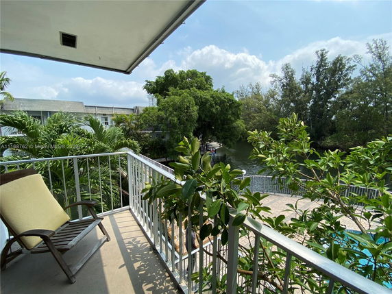 Balcony view overlooking a body of water and greenery.