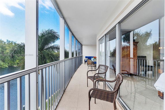 Outdoor balcony with glass railings and a view of trees and water.