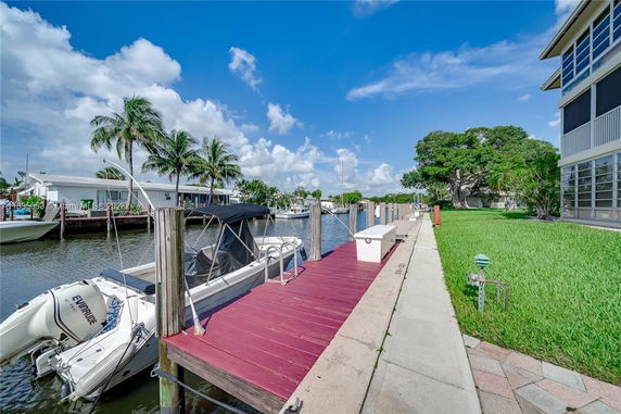 View of a dock and waterfront area with boats and palm trees.