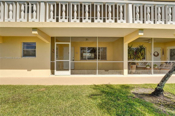 Front view of a two-story building with a screened porch and decorative railing on the upper level.