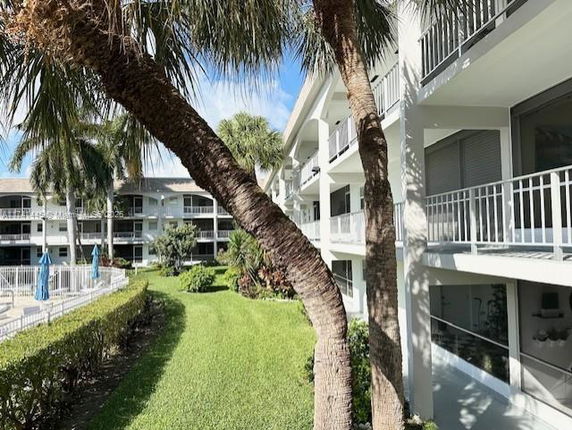 Exterior view of a multi-story residential building with balconies and surrounding greenery.