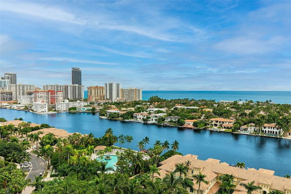Aerial view of a waterfront area with waterfront homes, high-rise buildings, and ocean in the distance.