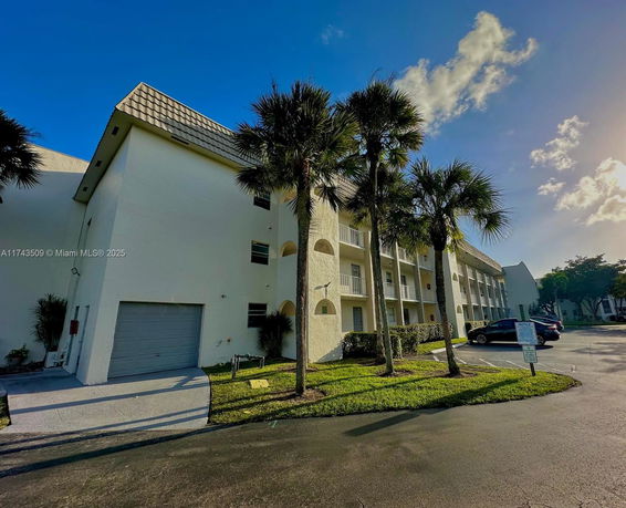 Front view of a multi-story residential building with a sloped roof and balconies.
