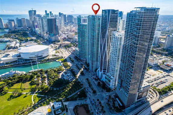 Aerial view of a cluster of high-rise buildings in a cityscape with surrounding areas including a park, roads, and a body of water nearby.