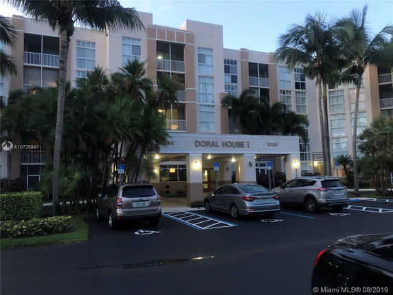 Front view of a multi-story residential building with parking area.