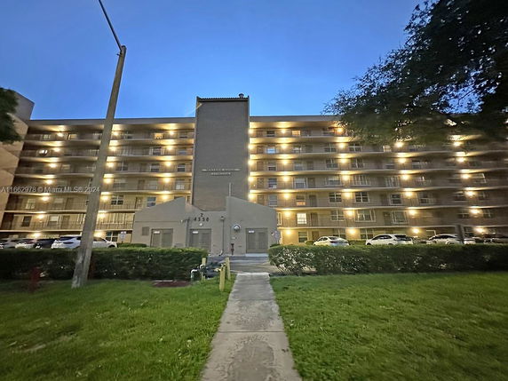 Front view of a multi-story residential building with exterior lighting.