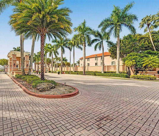 View of palm trees lining a pathway in front of a multi-story building.