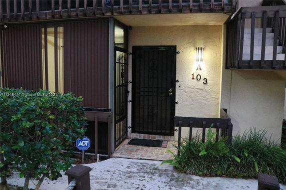 Entrance of a residential building with a gated door and balcony.