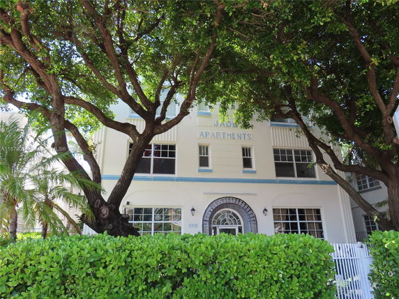 Front view of a multi-story apartment building with large windows and decorative entrance.