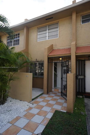 Front view of a two-story house with a tiled pathway and a small porch.