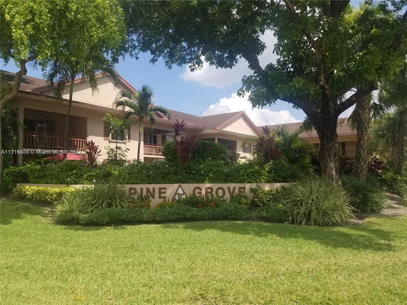 Front view of a residential building with a landscaped entrance and prominent sign.