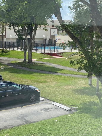 View of a swimming pool area with surrounding fence and a nearby parked car.